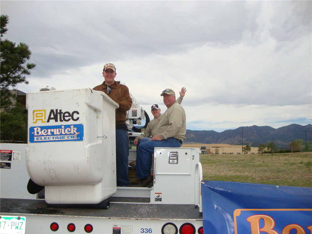 Berwick Electric guys hanging out on the bucket truck, getting ready to send Miles sky-high; Doug Berwick (Treasurer) and his son Miles Berwick (Warehouse/Driver), and Bill Tuten (Saftey Manager).